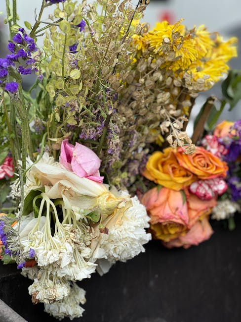 A close-up of multiple freshly cut floral bouquets featuring a variety of flowers including purple statice, yellow tansy, pink roses, white carnations, and green foliage, arranged together on a black 